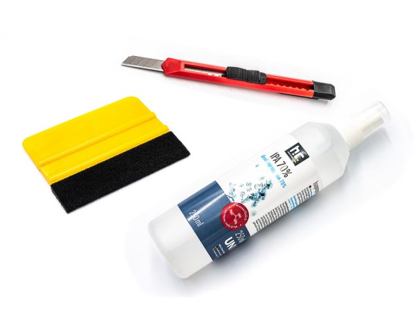 Kit de pose d'adhésif mural comprenant un flacon de nettoyage, un cutter rouge et une raclette d'application jaune