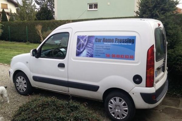 Adhésif publicitaire pose facile appliqué sur le latéral d'un Renault kangoo blanc.