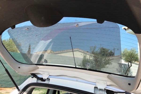 un plexipub posé sur une lunette arrière de voiture avec le coffre ouvert